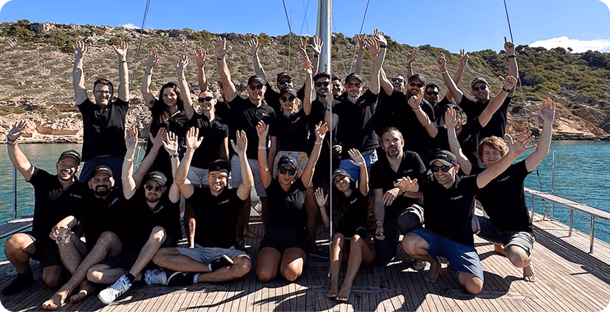Jaumo-Team feiert gemeinsam auf einem Boot mit erhobenen Armen — zeigt die freundliche, unterstützende Unternehmenskultur